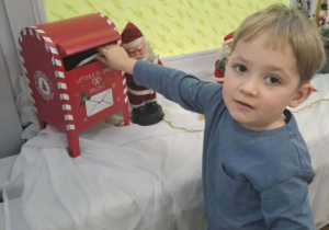 Chłopiec wrzuca list do skrzynki do Mikołaja.