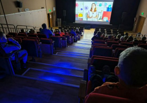 Dzieci siedzą i oglądają bajkę w kinie.