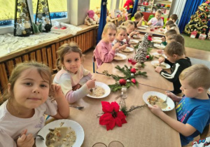 Dzieci siedzą przy wigilijnym stole.