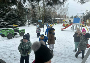 Dzieci bawią się na śniegu w zaśnieżonym ogrodzie przedszkolnym