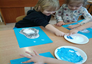 Dzieci maczają palce w farbie