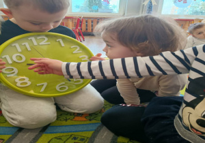 Chłopiec trzyma duży zegar ze wskazówkami