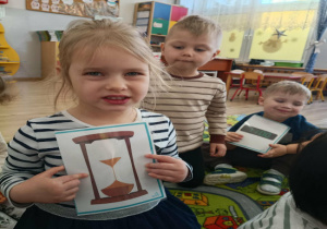 Dziewczynka pokazuje dzieciom zdjęcie klepsydry