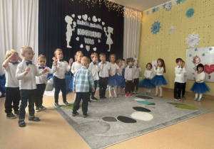 Dzieci stoją w szeregu i śpiewają piosenkę