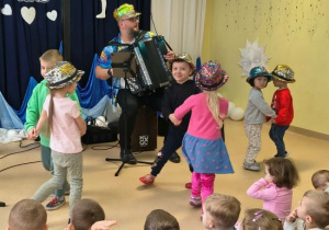 Dzieci tańczą w parach w cekinowych kapeluszach.