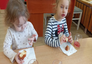 Dziewczynki siedzą przy stoliku i jedzą pączki.