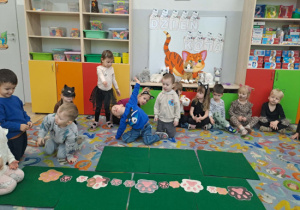 Dzieci układają rytmy z kocich śladów łap dużych i małych.