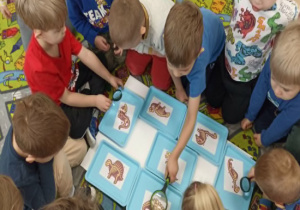 Dzieci oglądają przez lupę kości dinozaurów.