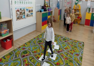 Dziewczynka idzie po ścieżce śladami dinozaura.