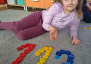 Blanka ułożyła numer 112 z kolorowych nakrętek.