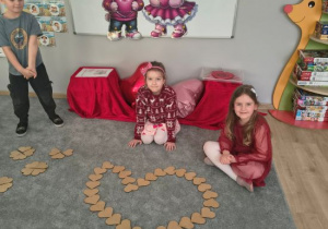 Dziewczynki układają kształty z małych drewnianych serc