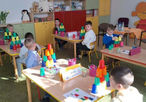 Dzieci rozwiązują zadanie z kubkami.