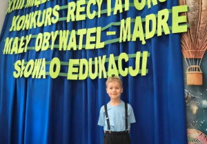 Olek stoi na tle dekoracji konkursowej.