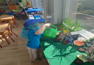 Chłopiec podlewa kwiaty wodą z konewki.