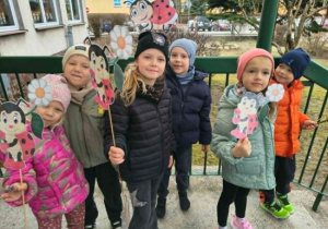 Dzieci stoją z emblematami wiosennymi.