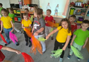 Dzieci tańczą taniec motyli z kolorowymi chustkami.