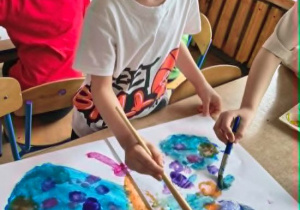 Aleks maluje farbami motyla.