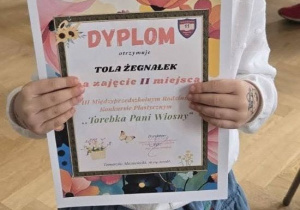 Tola prezentuje swój dyplom.