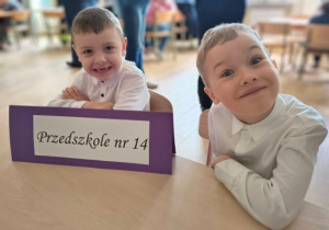Chłopcy siedzą przy swoim stanowisku.