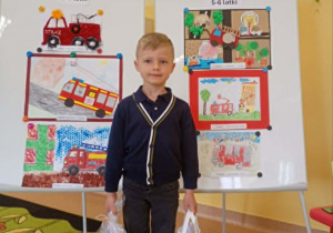 Olek stoi na tle nagrodzonych prac.