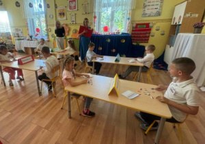 Dzieci rozwiązują zadania konkursowe przy stolikach.