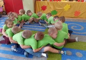 Dzieci siedzą w okręgu i przytulają się do siebie.