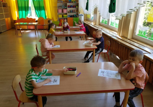 Dzieci kolorują obrazek przy stolikach