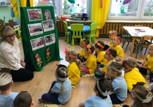 Dzieci słuchają opowiadania nauczyciela.