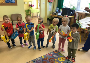 Dzieci najmłodsze podczas gry na dmuchanych instrumentach.