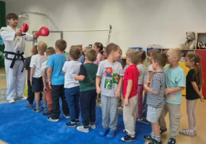 Dzieci stoją w kolejce przed trenerem.
